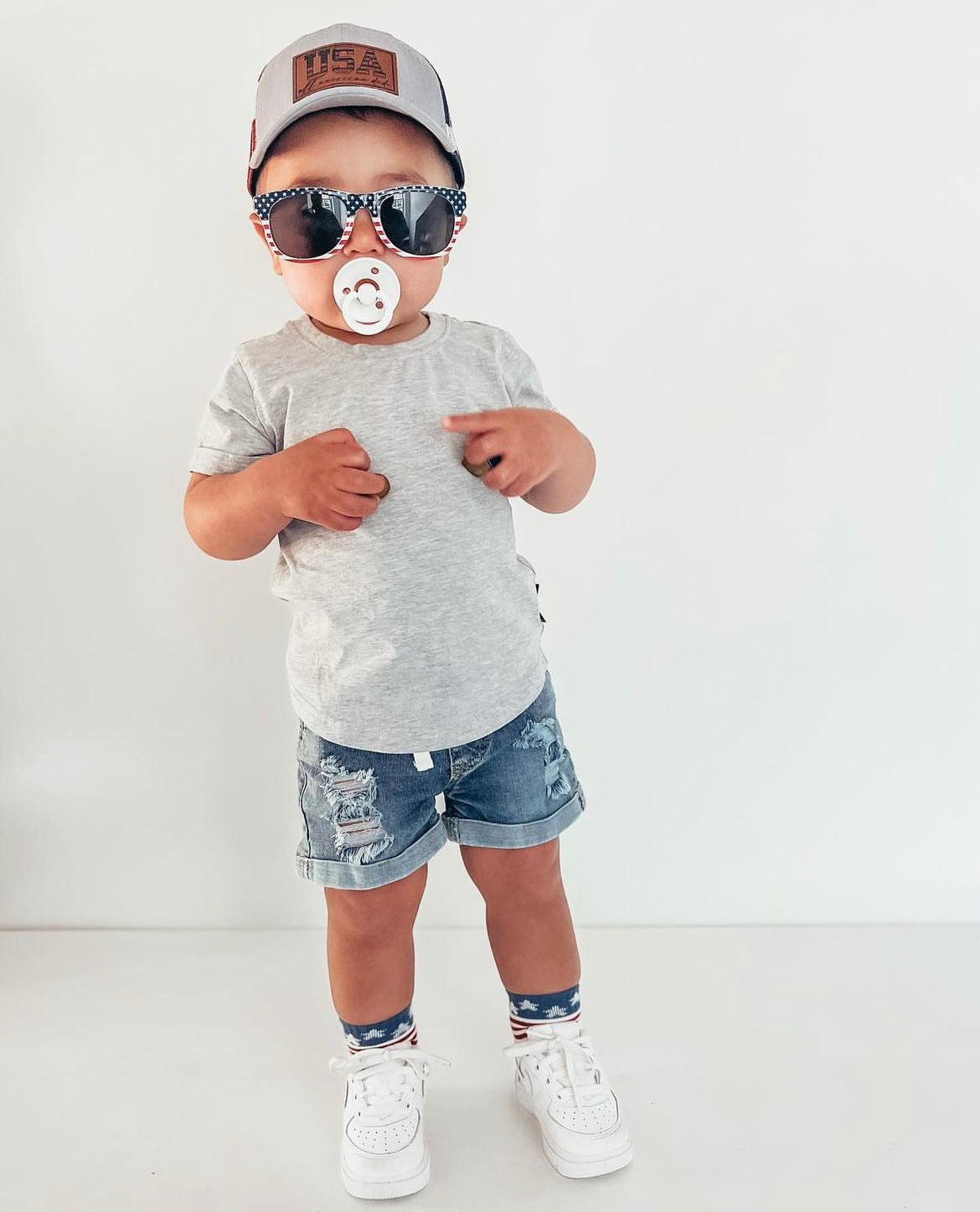 Baby in kids trendy outfit. Kids basic tee in grey and kids denim distressed shorts.