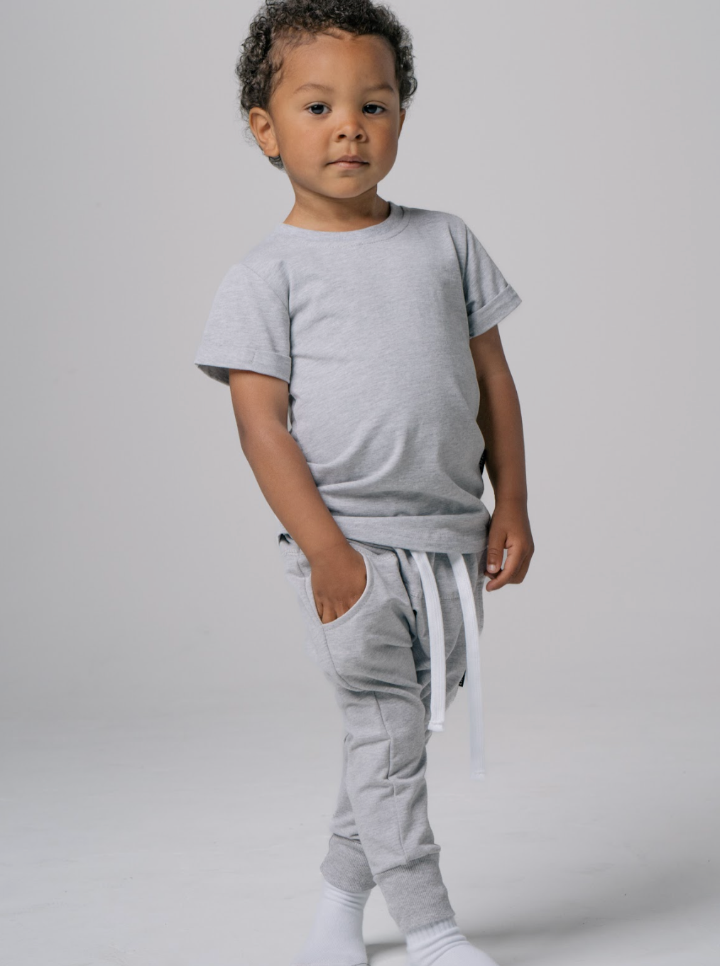 Kid in kids sweats outfit. Kids basic tee in grey and matching kids sweatpants.